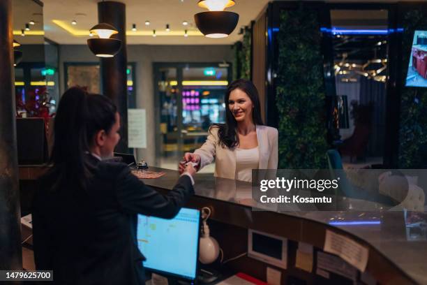 la recepcionista le da a la mujer de negocios una tarjeta de acceso en la recepción del hotel - identity card fotografías e imágenes de stock