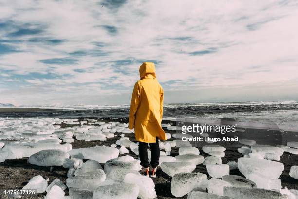unrecognizable person on diamond beach in iceland. - black sand iceland stock-fotos und bilder