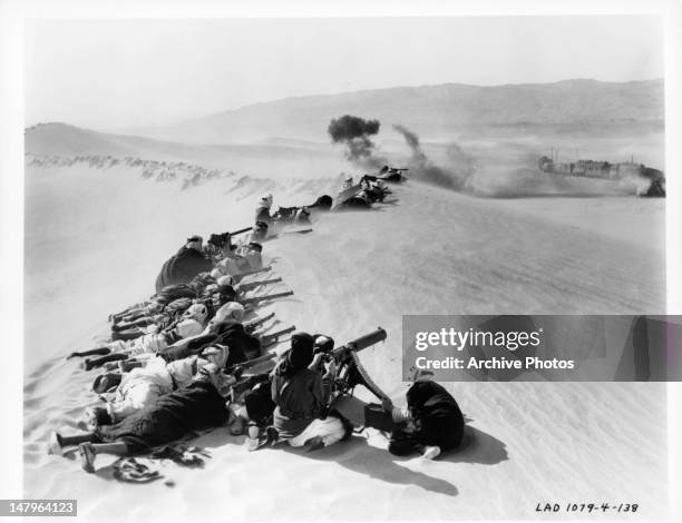 Men firing on train from sand dune in a scene from the film 'Lawrence Of Arabia', 1962.