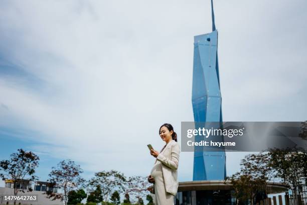 schwangere asiatische geschäftsfrau mit smartphone in der stadt - merdeka 118 stock-fotos und bilder