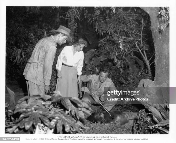 Phillip Terry, Coleen Gray, and John Van Dreelen discover one of their native helpers mysteriously killed in a scene from the film 'The Leech Woman',...