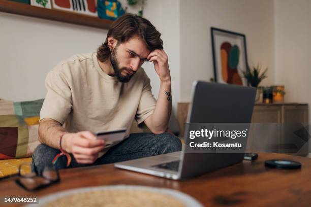 worried man looks at the laptop screen and realizes that he is a victim of an internet scam - slachtoffer stockfoto's en -beelden