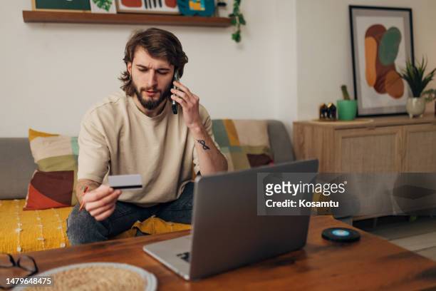male bank client notices a problem and is worried about a credit card problem, the threat of financial fraud - debit card fraud stock pictures, royalty-free photos & images