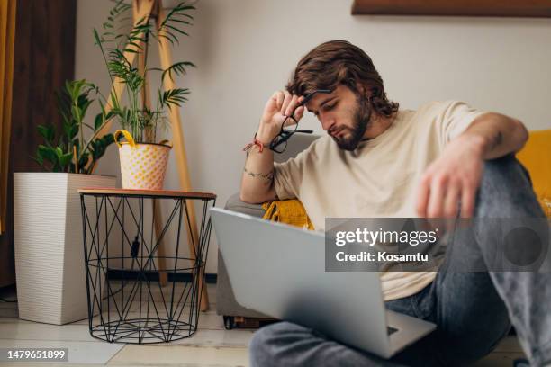 concerned man looking at laptop screen and trying to figure out what's wrong with a transaction he's trying to make using a credit card - victim stock pictures, royalty-free photos & images