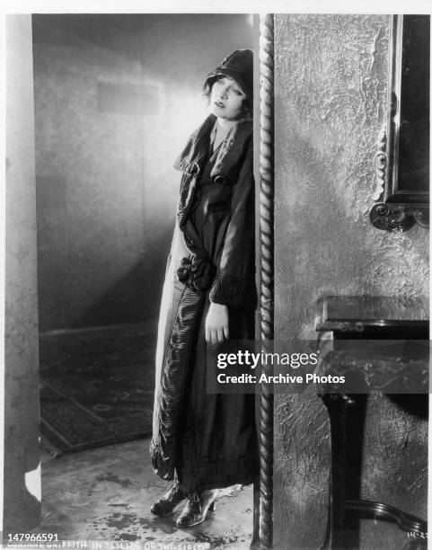 Corinne Griffith leans inside a doorway in a scene from the film 'Lilies Of The Field', 1930.