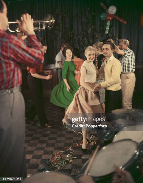 Party scene with a group of young people on a dancefloor dancing to the music of a jazz band, London, 27th December 1958.