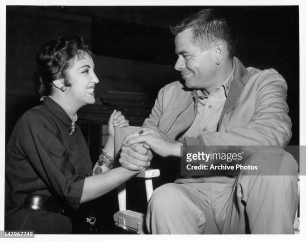 Katy Jurado and Glenn Ford sharing a smile on the set of the film 'Torpedo Run', 1958.