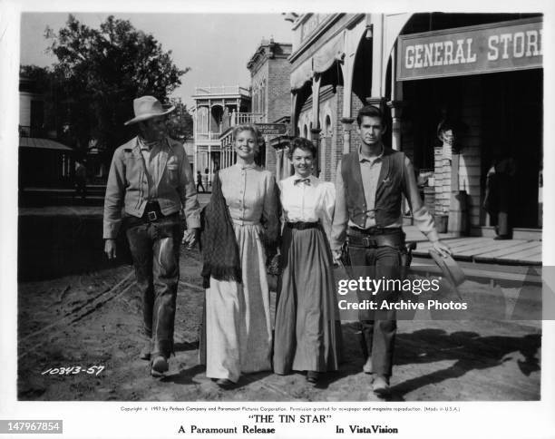 Henry Fonda, Betsy Palmer, Mary Webster, and Anthony Perkins walking together in the town square in a scene from the film 'The Tin Star', 1957.