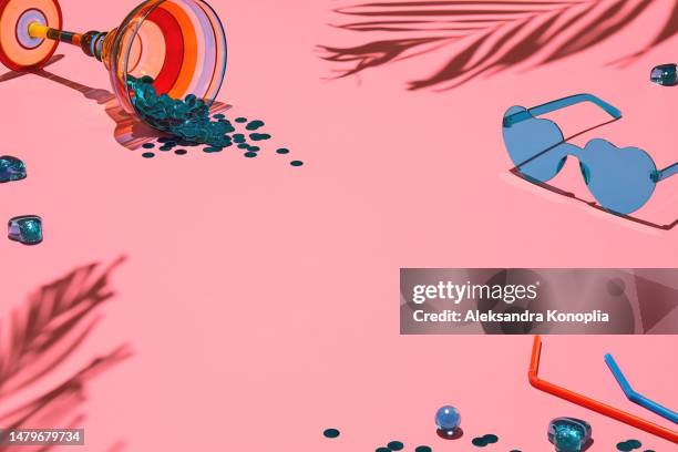 summer flat lay - tropical palm shadows, heart shaped sunglasses and cocktail glass filled with confetti on soft pink background - holiday cocktail flat lay stock pictures, royalty-free photos & images