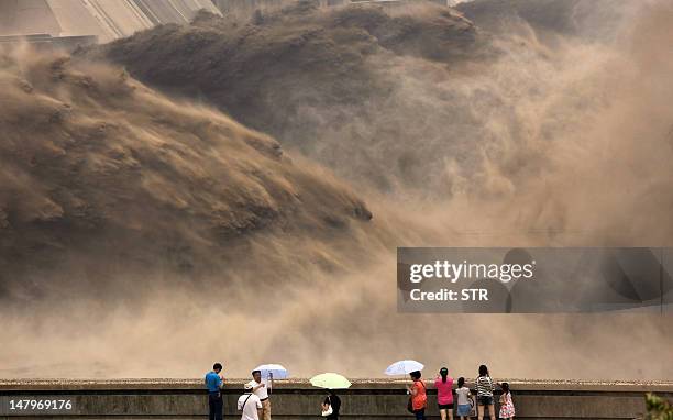 This picture taken on July 6, 2012 shows visitors gathering to watch giant gushes of water being released from the Xiaolangdi dam to clear up the...