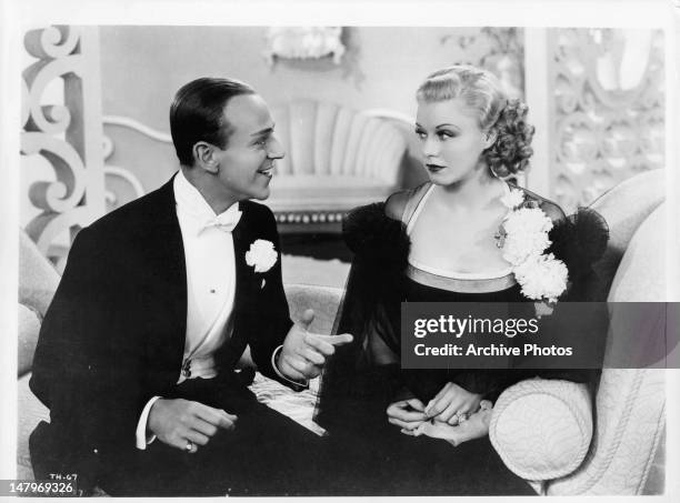 Fred Astaire talking to Ginger Rogers on couch in a scene from the film 'Top Hat', 1935.