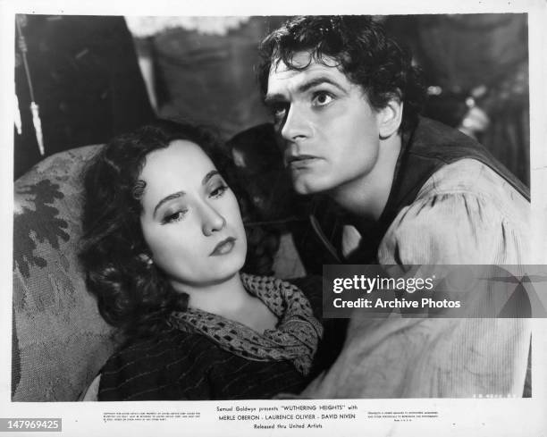 Merle Oberon on the couch with Laurence Olivier abover her in a scene from the film 'Wuthering Heights', 1939.