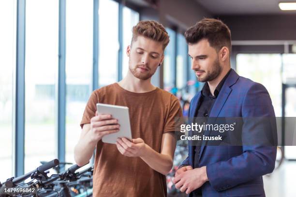 salesman and male customer in bicycle shop - product life cycle stock pictures, royalty-free photos & images