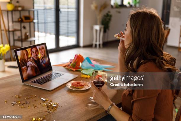 young woman enjoying a glass of red wine while video chatting with friends for her birthday - zoom birthday stock pictures, royalty-free photos & images