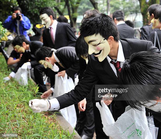 People wearing masks attend a clean up mission organised by hacker collective Anonymous on a street in Tokyo on July 7, 2012. Anonymous is a...