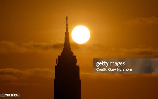 The sun rises behind the Empire State Building in New York City on April 4 as seen from Jersey City, New Jersey.