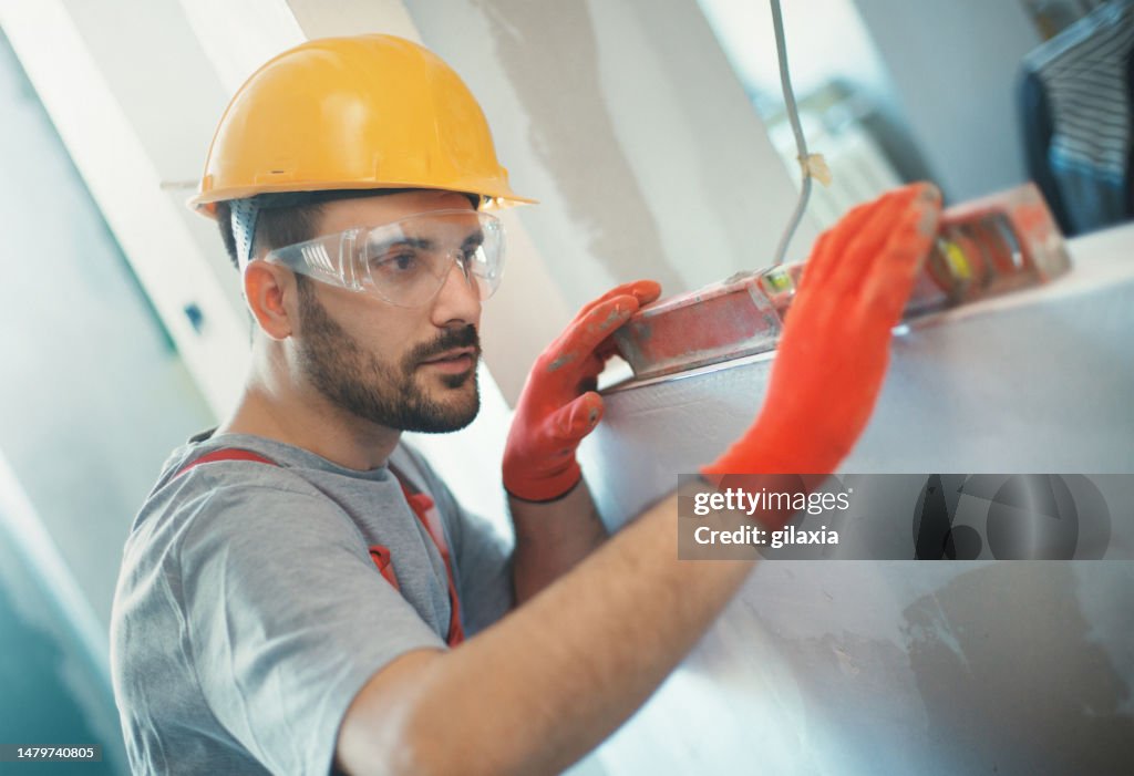 Trabalhador da construção civil realizando algumas medições.