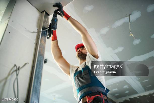 construction worker assembling a drywall. - plasterer stock pictures, royalty-free photos & images