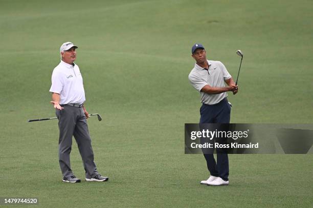 Fred Couples of the United States talks with Tiger Woods of the United States as he plays a shot on the eighth hole during a practice round prior to...