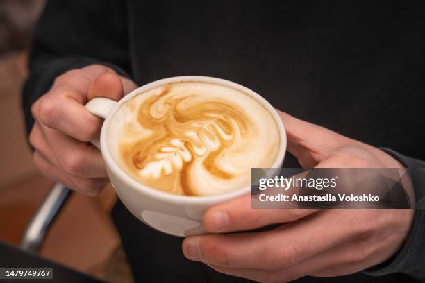 men holds coffee cup of specialty coffee, cappuccino. close-up - dieta a base de plantas fotografías e imágenes de stock