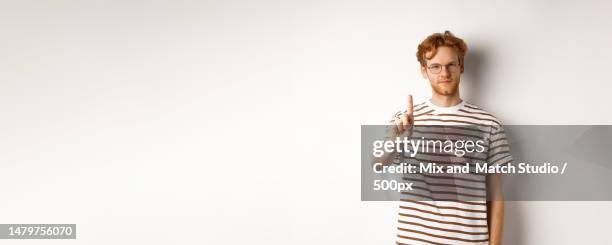 young man with red hair and glasses shaking finger in prohibition - shaking finger stock pictures, royalty-free photos & images