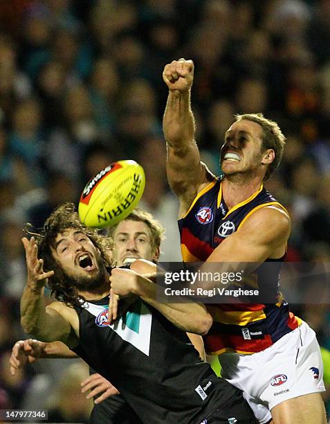 Ben Rutten of the Crows punches the ball away from John Butcher of the Power during the round 15 AFL match between the Port Adelaide Power and the...