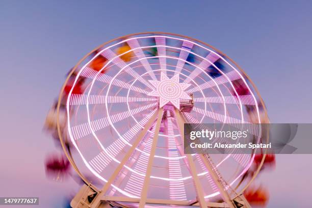 illuminated ferris wheel in tibidabo amusement park spinning after sunset, barcelona, spain - tibidabo fotografías e imágenes de stock
