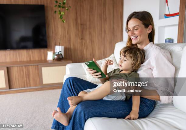 loving mother and son watching videos on a cell phone - mother media call stock pictures, royalty-free photos & images