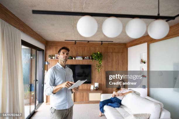 man controlling the lights in his house using an automated system - home automation stock pictures, royalty-free photos & images