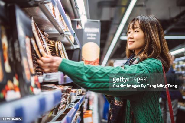 young pretty woman doing grocery shopping in supermarket - supermarket uk stock pictures, royalty-free photos & images