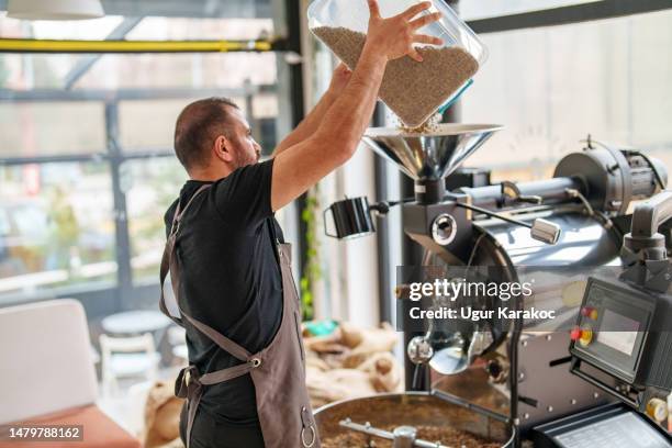 pouring raw coffee beans to roasting machine - coffee roasting stock pictures, royalty-free photos & images