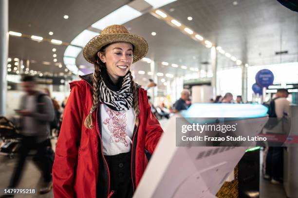 mujer que utiliza la máquina de autoservicio de check-in en el aeropuerto - tótem fotografías e imágenes de stock