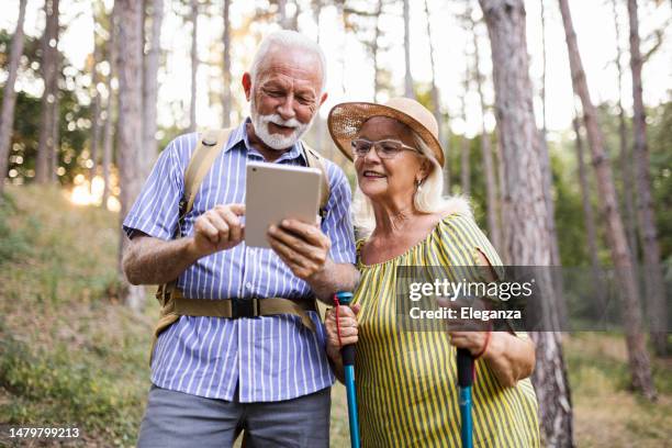 foto eines älteren paares mit digitalem tablet während seiner wanderung mit rucksäcken - tablet paar sommer stock-fotos und bilder