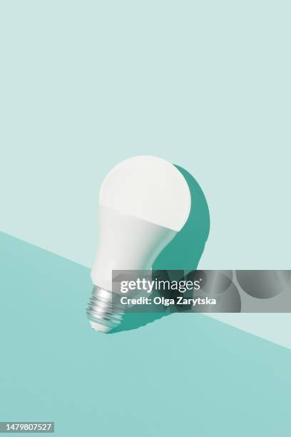 illuminated led light bulb in brightly lit on light blue background. - led lightbulb stock pictures, royalty-free photos & images