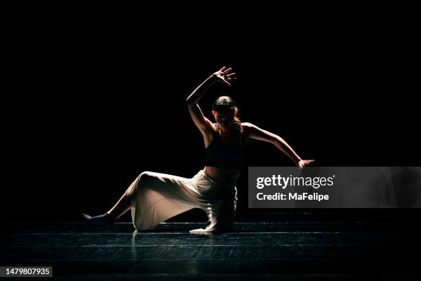 young girl performing contemporary dance on dark stage. - contemporary dance stock pictures, royalty-free photos & images