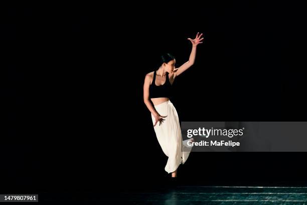 young girl performing contemporary dance on dark stage. - contemporary dance stock pictures, royalty-free photos & images