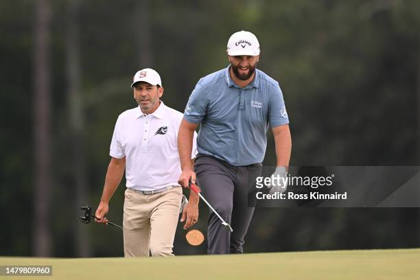 Sergio Garcia of Spain and Jon Rahm of Spain laugh on the ninth green during a practice round prior to the 2023 Masters Tournament at Augusta...