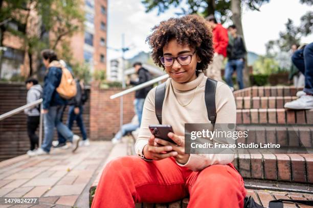young university student using mobile phone on stairs outdoors - laatstejaars high school stockfoto's en -beelden