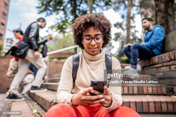 giovane studente universitario che utilizza il telefono cellulare sulle scale all'aperto - 18 19 anni foto e immagini stock