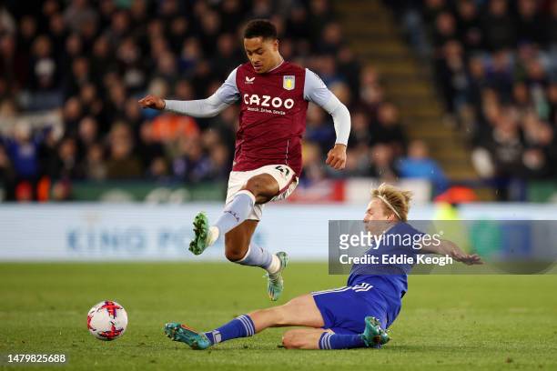 Jacob Ramsey of Aston Villa jumps over Victor Kristiansen of Leicester City as they attempt to tackle during the Premier League match between...