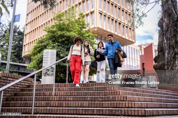 young university students talking while walking down the stairs at university - campus imagens e fotografias de stock