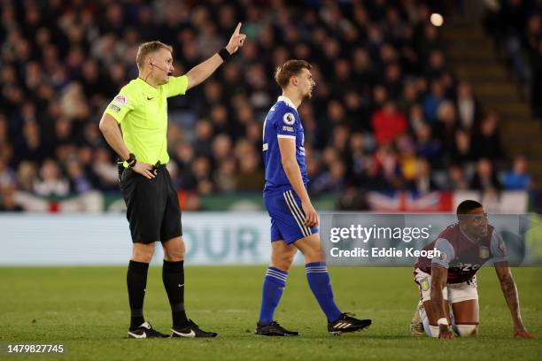 Referee Graham Scott gestures after showing a red card to Kiernan Dewsbury-Hall of Leicester City after tackling Ashley Young of Aston Villa during...