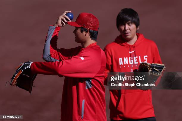 Shohei Ohtani of the Los Angeles Angels warms up next to interpreter Ippei Mizuhara before the game against the Seattle Mariners at T-Mobile Park on...
