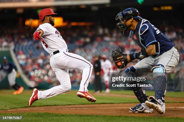 Jeimer Candelario of the Washington Nationals slides in to score on a two-run single off the bat of Alex Call behind catcher Christian Bethancourt of...