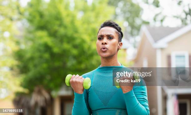 african-american woman exercising outdoors - bicep curl stockfoto's en -beelden