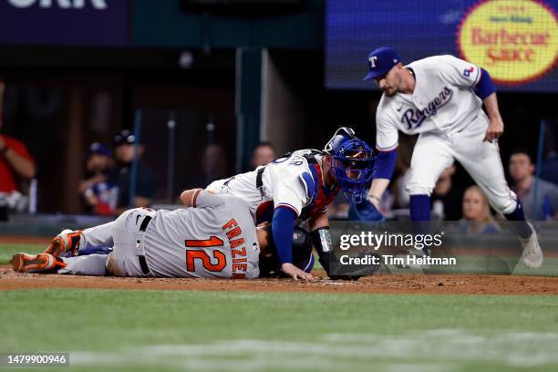 Mitch Garver of the Texas Rangers lays on top of Adam Frazier of the Baltimore Orioles in the second inning at Globe Life Field on April 04, 2023 in...