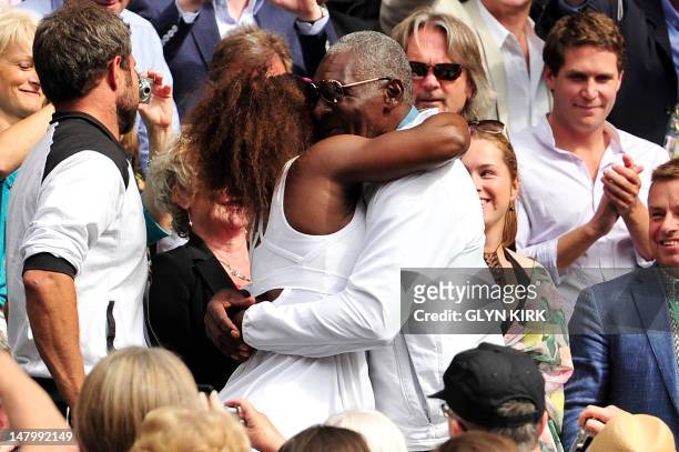 Player Serena Williams climbs up into the Royal Box to embrace her father Richard WIlliams after her women's singles final victory over Poland's...
