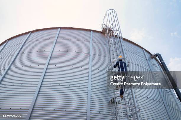 a workers are climbing onto a large water tank to inspect the water level in the water tank of the industrial estate waterworks authority. green industry concept or environmental conservation. - water pump ストックフォトと画像