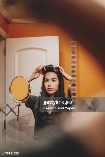 pretty young latina in bathroom with hair curlers - hair curlers stockfoto's en -beelden