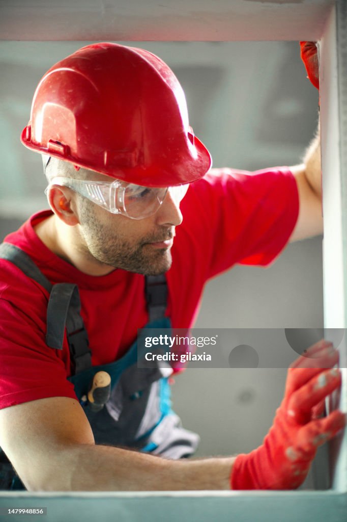 Construction worker assembling a drywall.